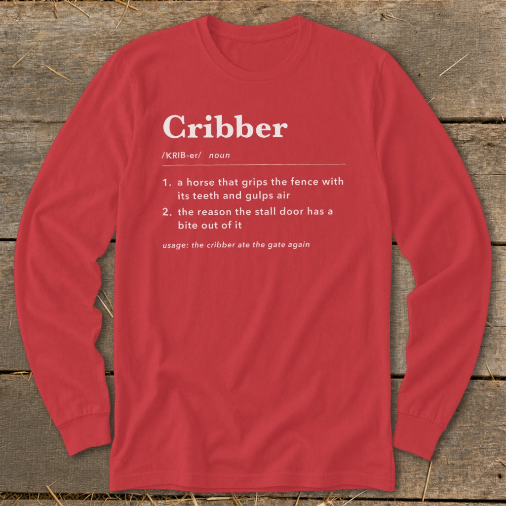 A red long-sleeve t-shirt with white text defining the word cribber laid on a wooden surface.