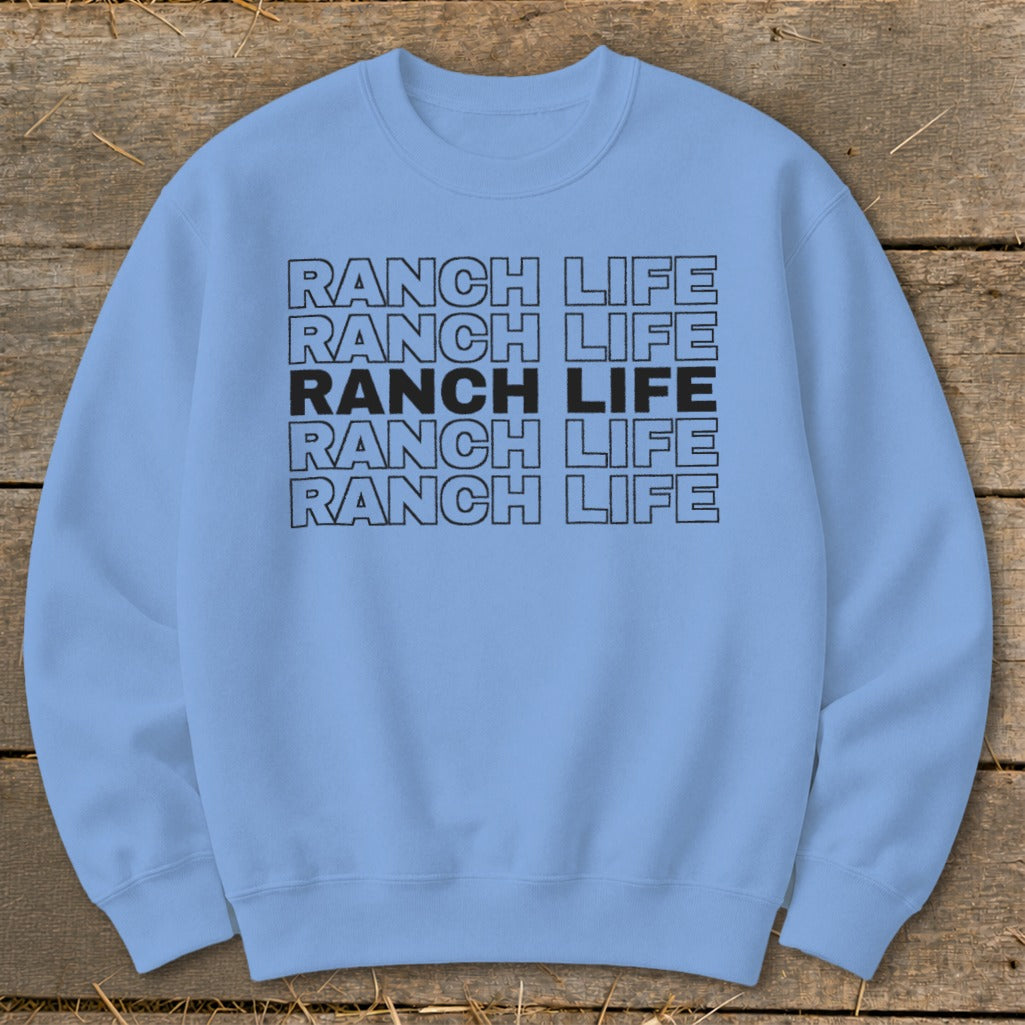 Light blue crewneck sweatshirt featuring the text Ranch Life repeated in five stacked rows, displayed on a rustic wooden background.
