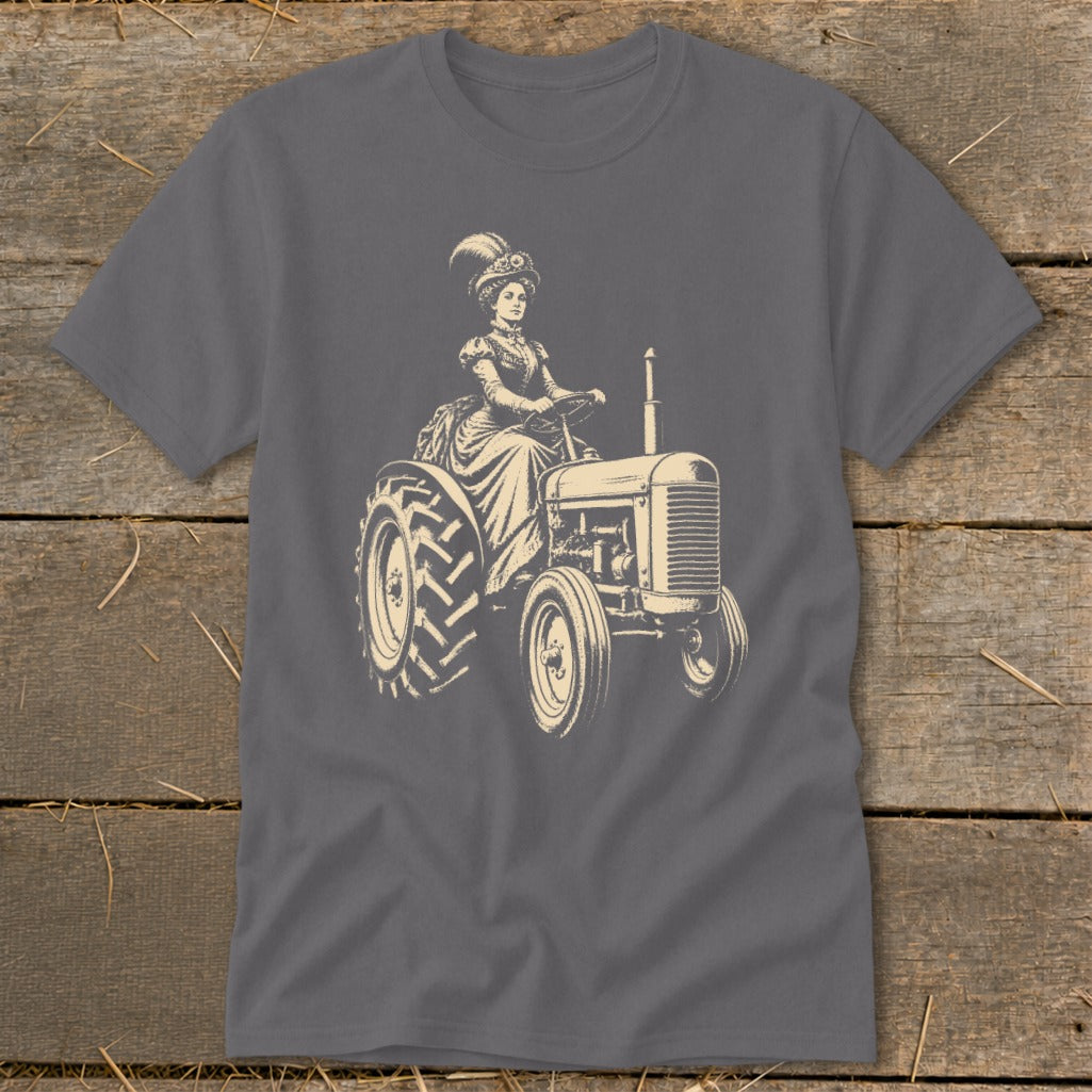 Woman in vintage dress and hat driving a tractor, graphic print on gray t-shirt.