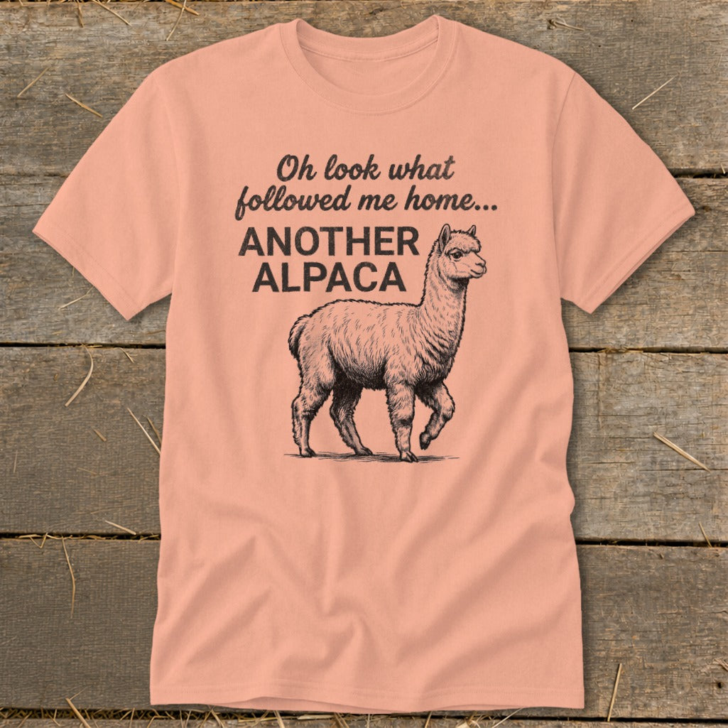 Peach t-shirt with a sketch of an alpaca and text: "Oh look what followed me home... ANOTHER ALPACA"