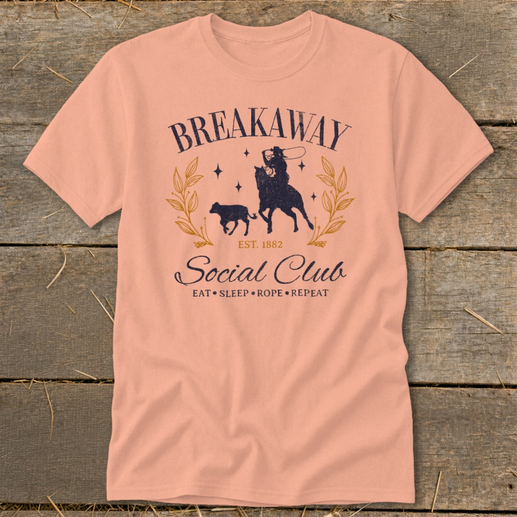 Peach t-shirt with "Breakaway Social Club" text and a cowboy roping a calf graphic.