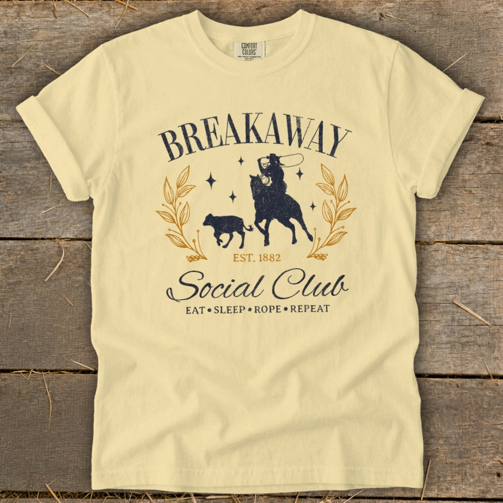 Cream t-shirt with "Breakaway Social Club" graphic of a cowboy on a horse roping a calf.
