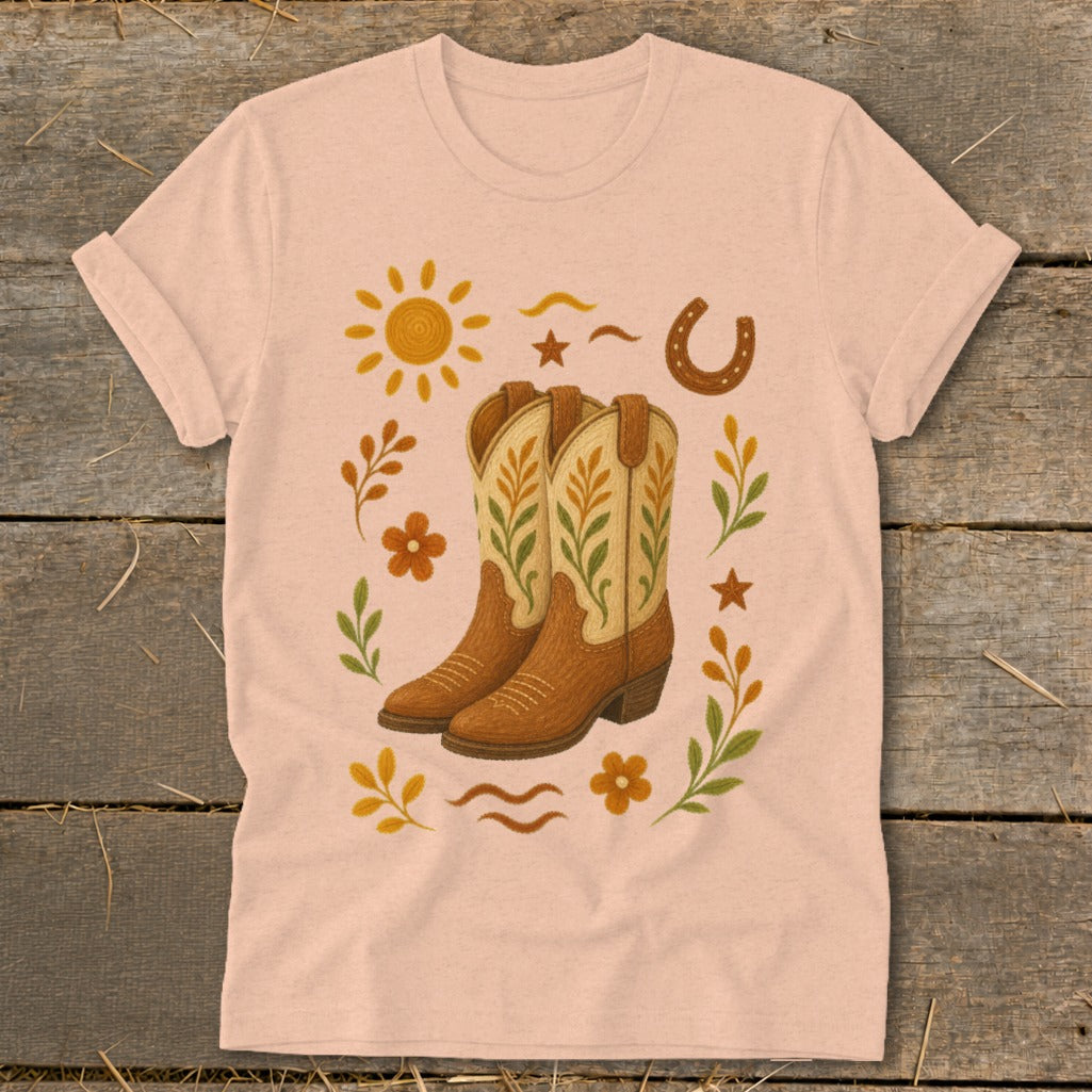 Pink t-shirt with cowboy boots, sun, horseshoe, and floral Western graphic.