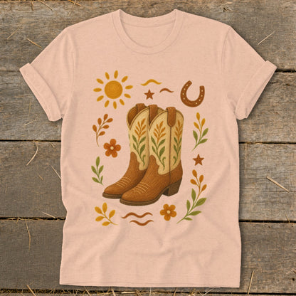 Pink t-shirt with cowboy boots, sun, horseshoe, and floral Western graphic.