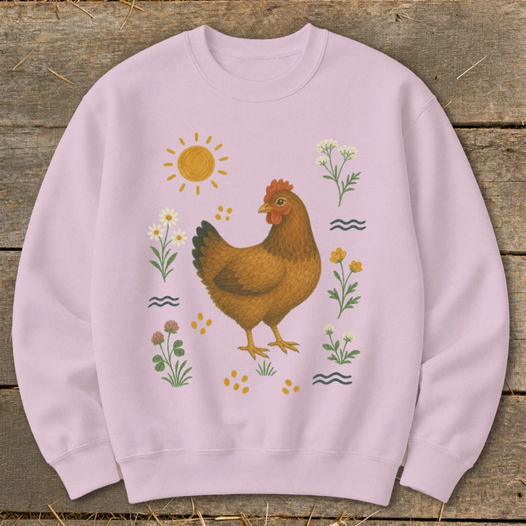 Light pink sweatshirt with a brown hen surrounded by flowers, sun, and water waves.