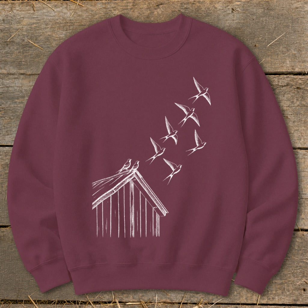 A maroon crewneck sweatshirt features a white line graphic of birds flying off a roof.