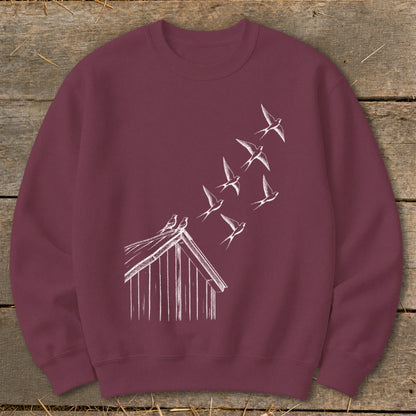A maroon crewneck sweatshirt features a white line graphic of birds flying off a roof.