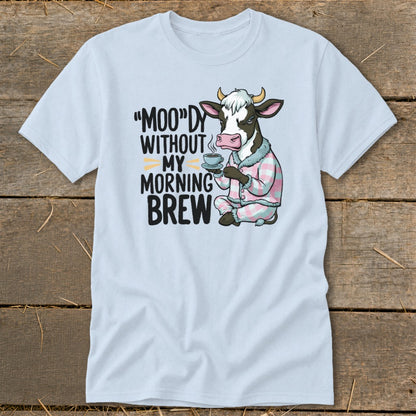 Light blue t-shirt with a cartoon cow in pajamas holding coffee and text "MOO"dy without my morning brew."