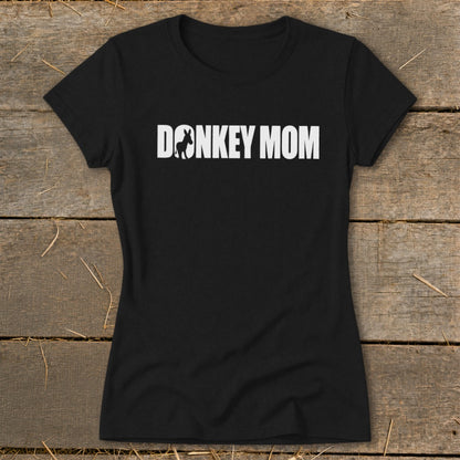 A black women's crew neck t-shirt featuring the white text DONKEY MOM with a donkey silhouette inside the letter O, laid on wooden boards.