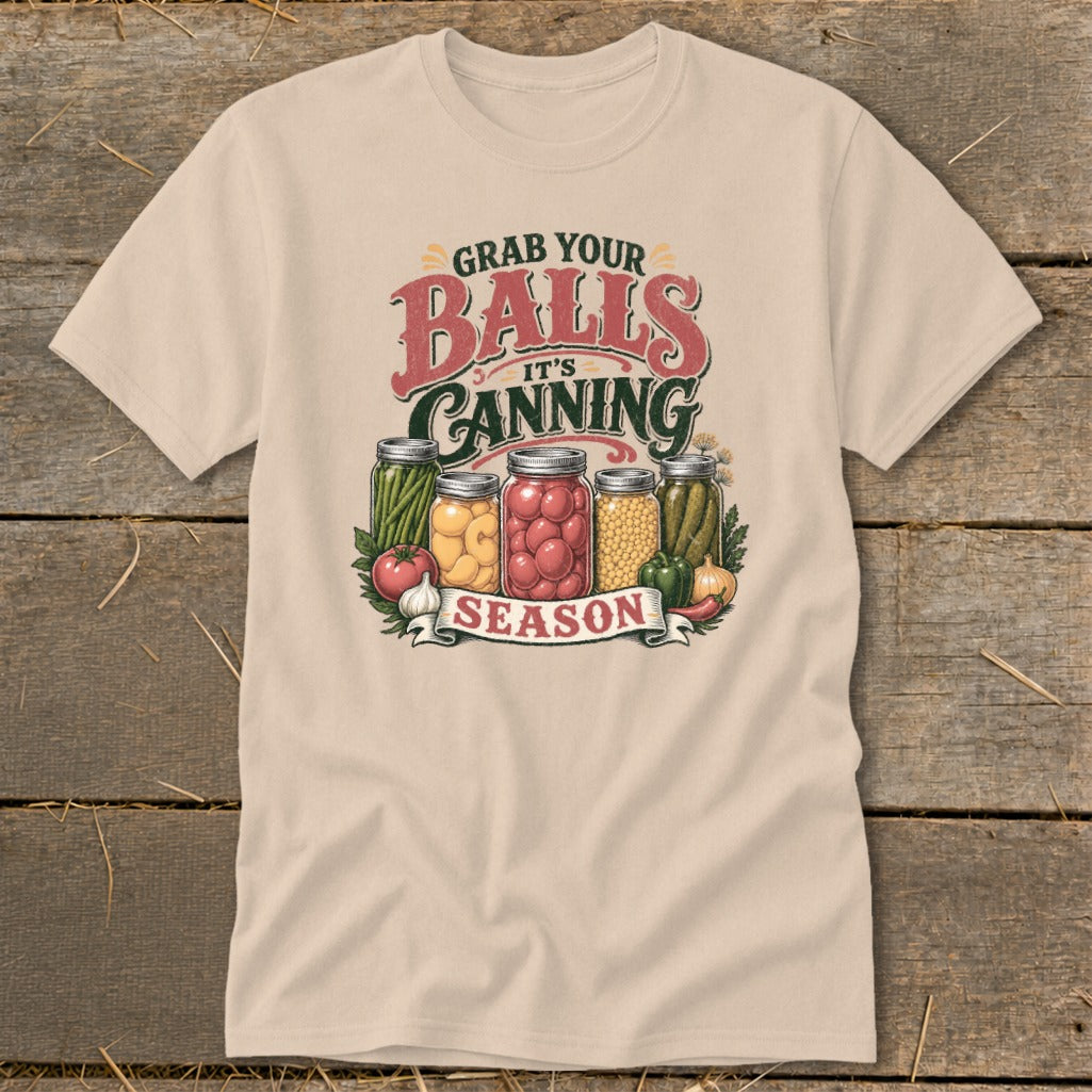 T-shirt graphic with text "Grab Your Balls It's Canning Season" and jars of preserved produce.