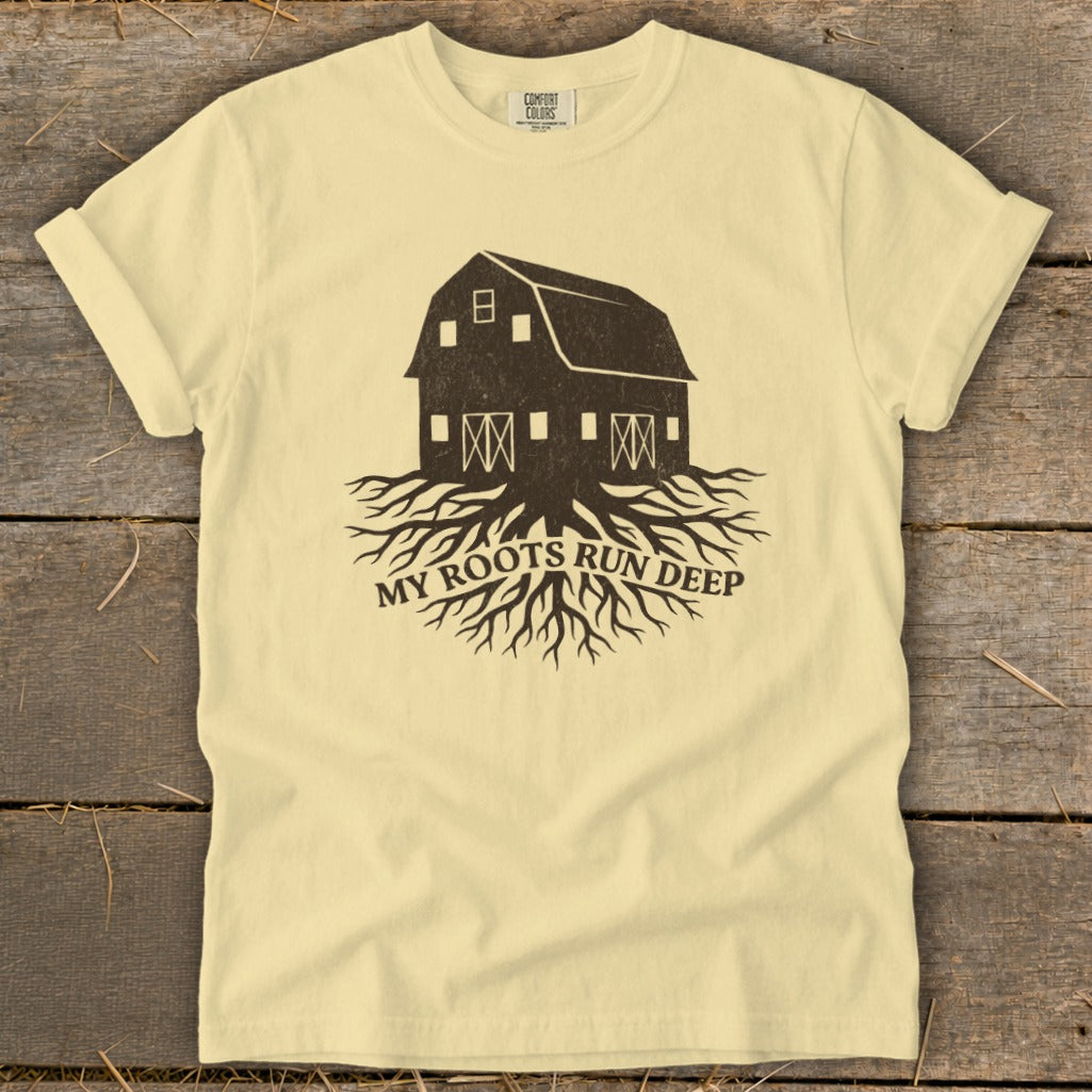 Pale yellow t-shirt with dark brown barn and roots graphic, text "MY ROOTS RUN DEEP."