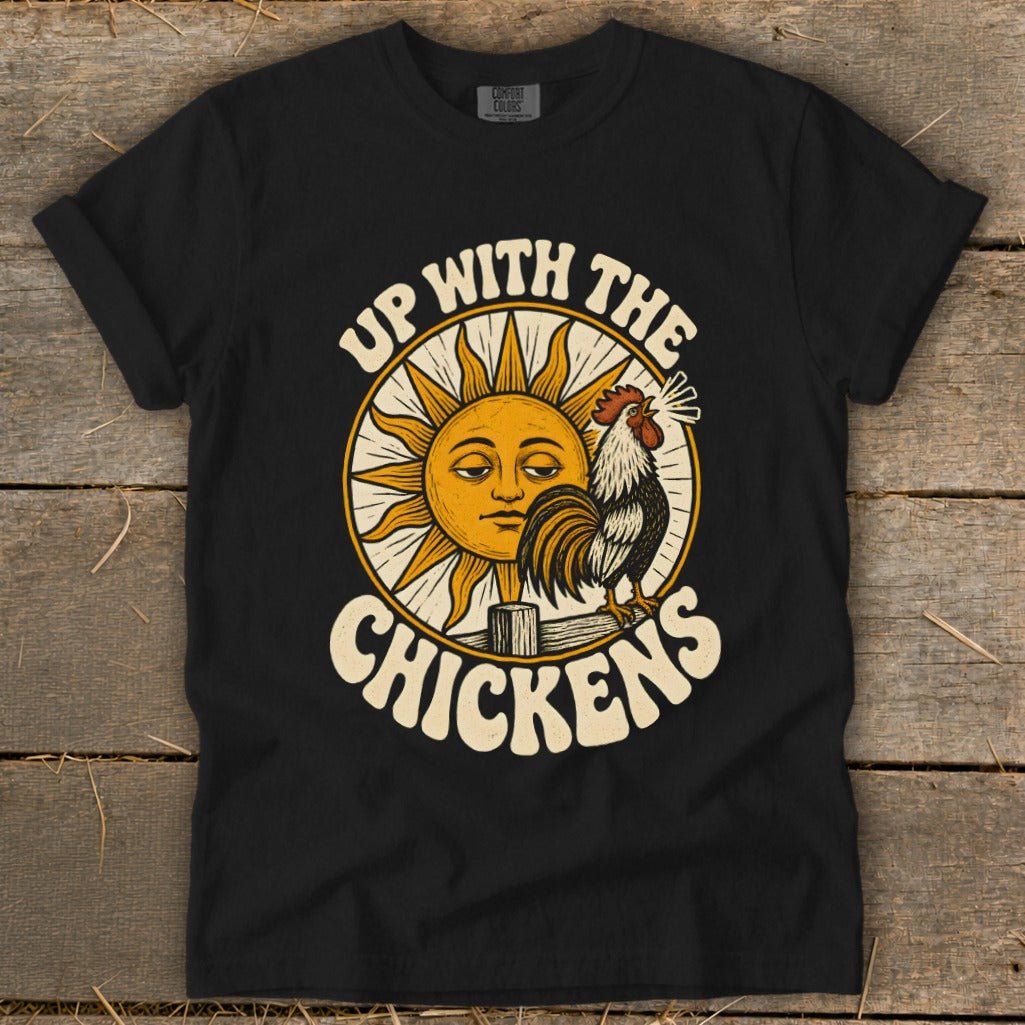A black t-shirt features a vintage-style graphic of a rooster and a sun, with the text "Up With the Chickens."