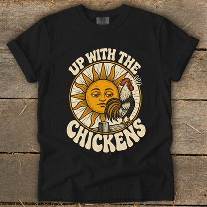 A black t-shirt features a vintage-style graphic of a rooster and a sun, with the text "Up With the Chickens."