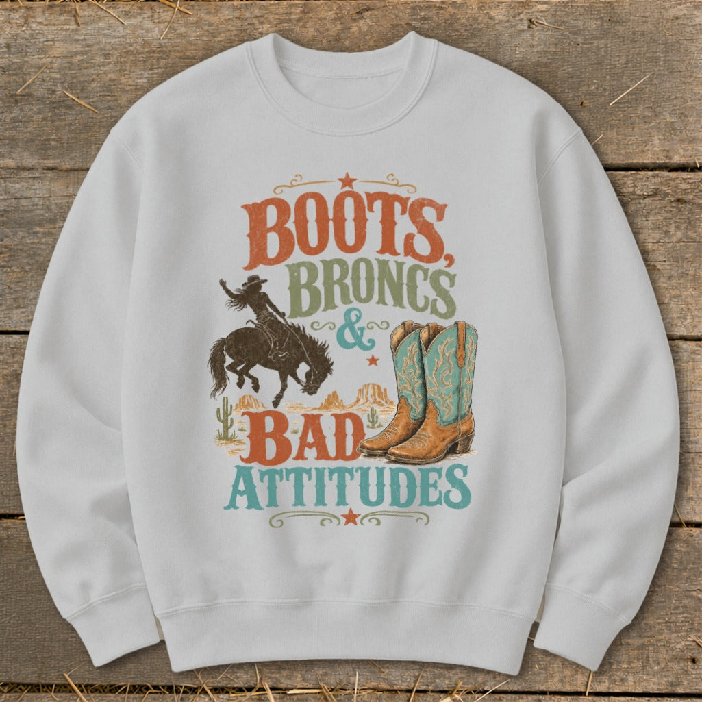 White sweatshirt with "Boots, Broncs & Bad Attitudes" graphic and cowboy imagery.