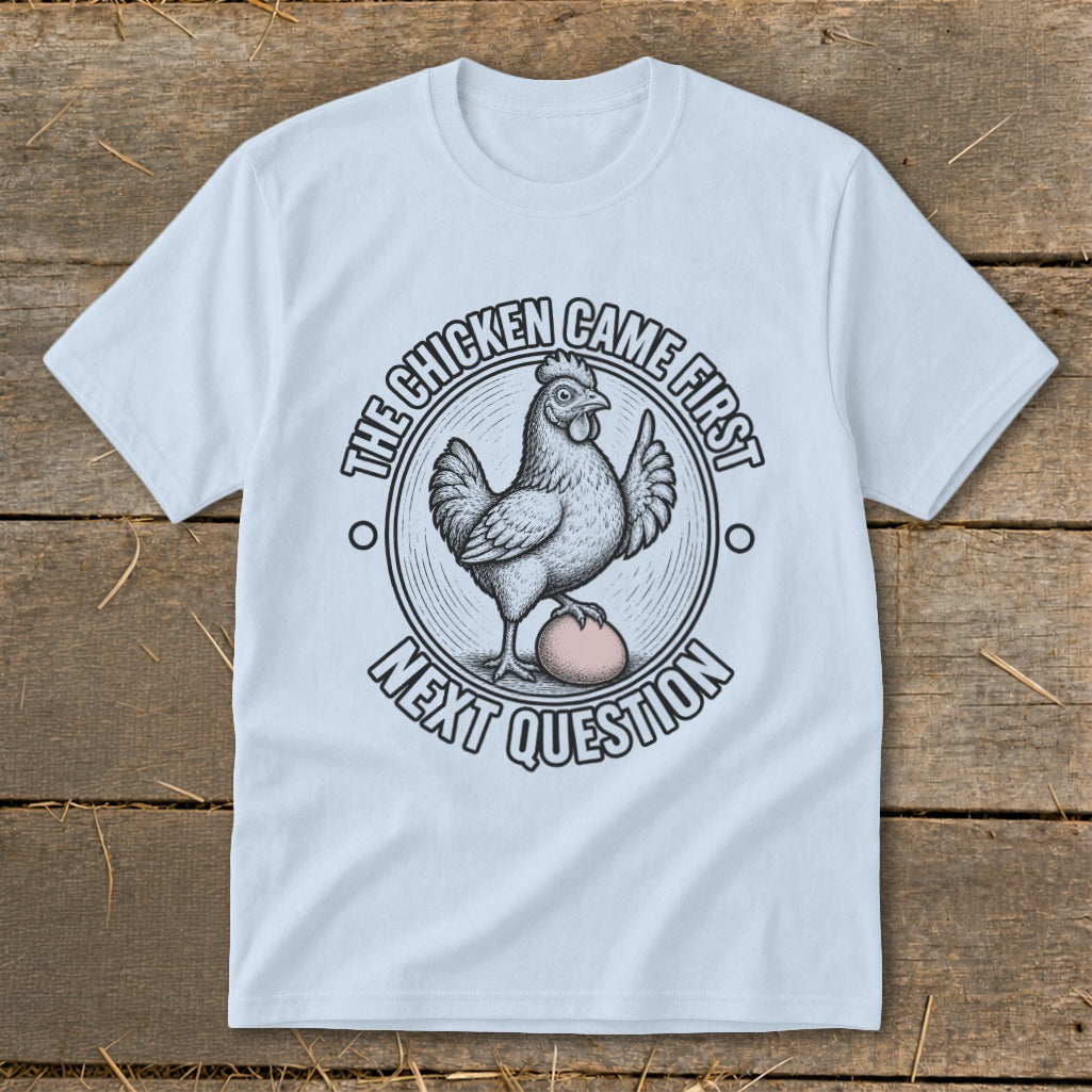 Light blue t-shirt with a chicken and egg graphic saying "The chicken came first. Next question."