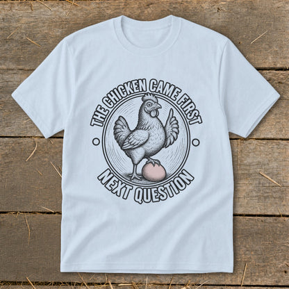 Light blue t-shirt with a chicken and egg graphic saying "The chicken came first. Next question."