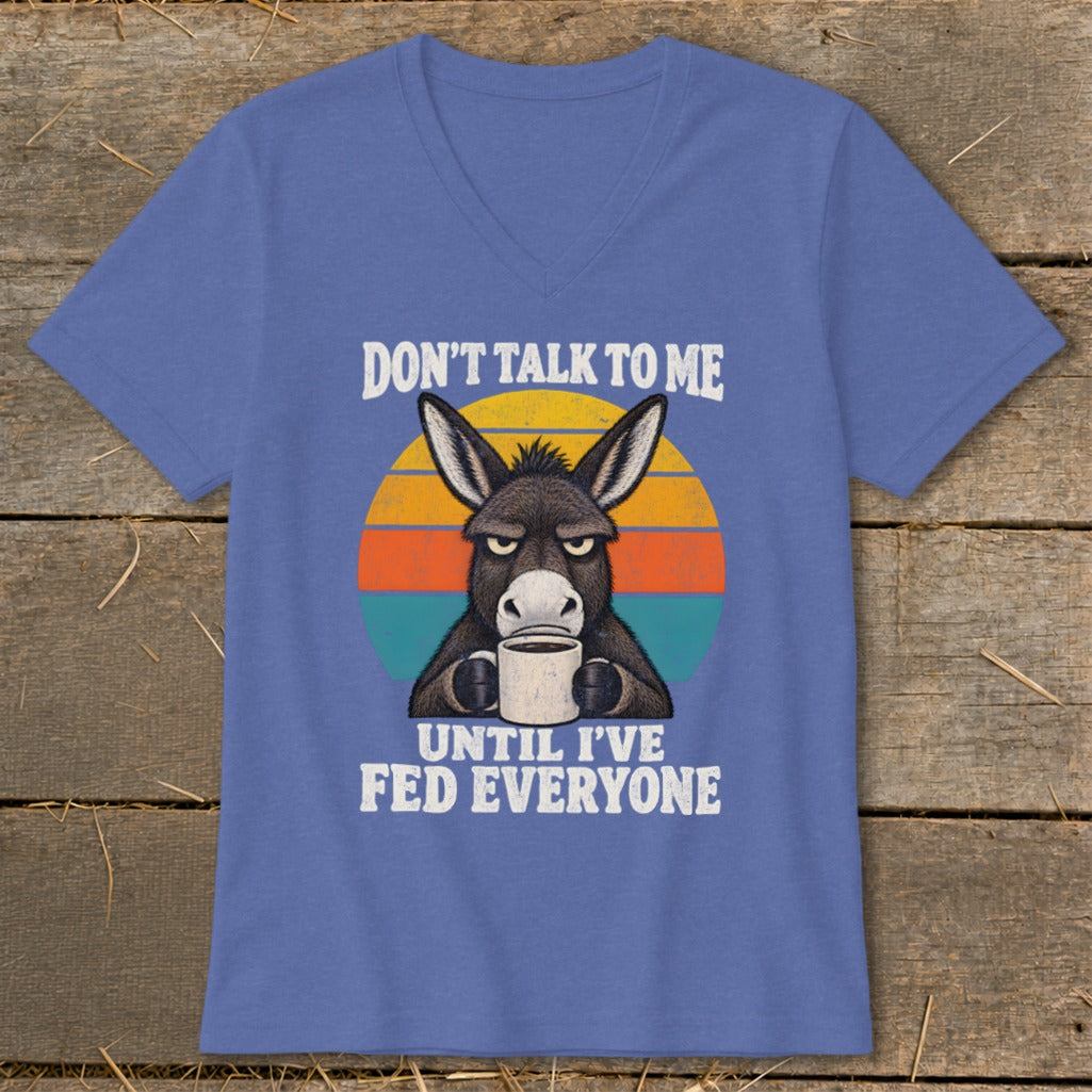 Blue V-neck t-shirt featuring a graphic of a grumpy donkey holding a coffee mug and text reading Don't Talk to Me Until I've Fed Everyone.