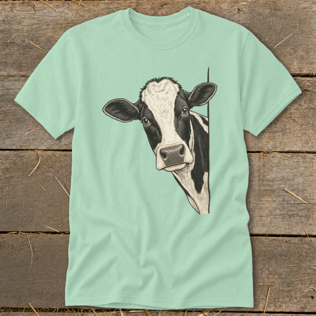 Black and white cow peeking from behind a corner on a pale green t-shirt.