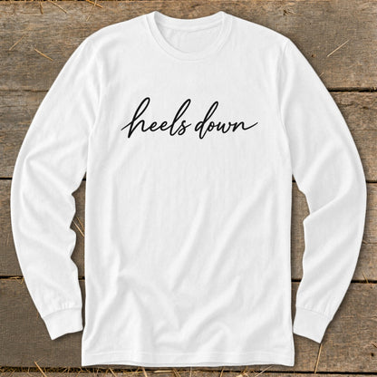 White long-sleeve shirt with "heels down" text in black cursive lettering.