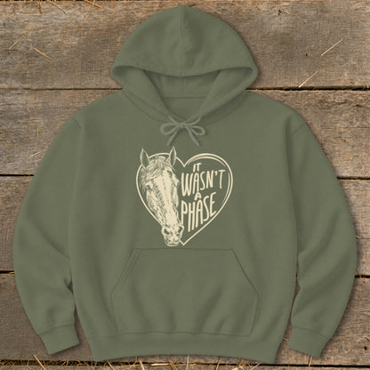 Olive green hoodie with a cream heart graphic featuring a horse and text "IT WASN'T A PHASE".