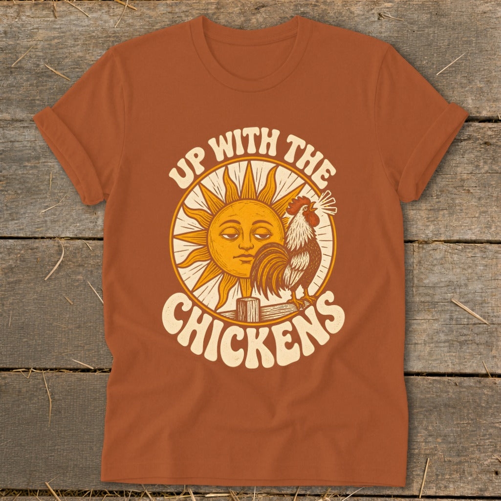 Orange t-shirt featuring a retro graphic of a crowing rooster, a smiling sun, and the text Up With The Chickens.