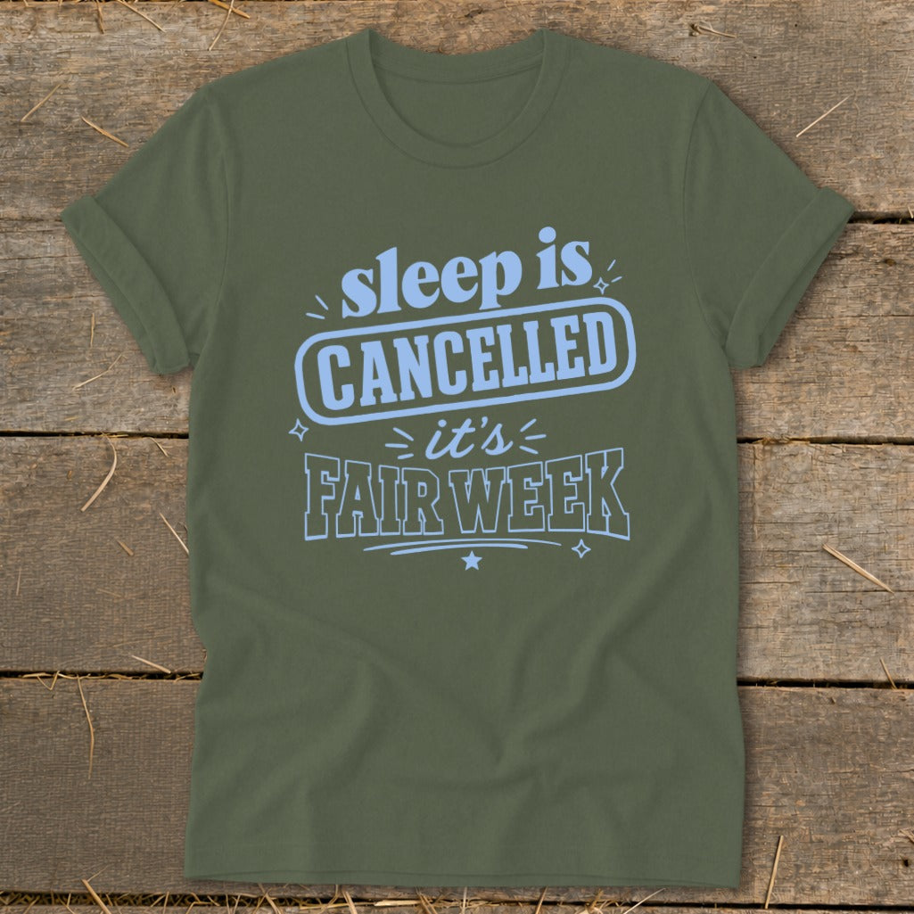Olive green t-shirt with light blue text that reads "sleep is CANCELLED it's FAIR WEEK".