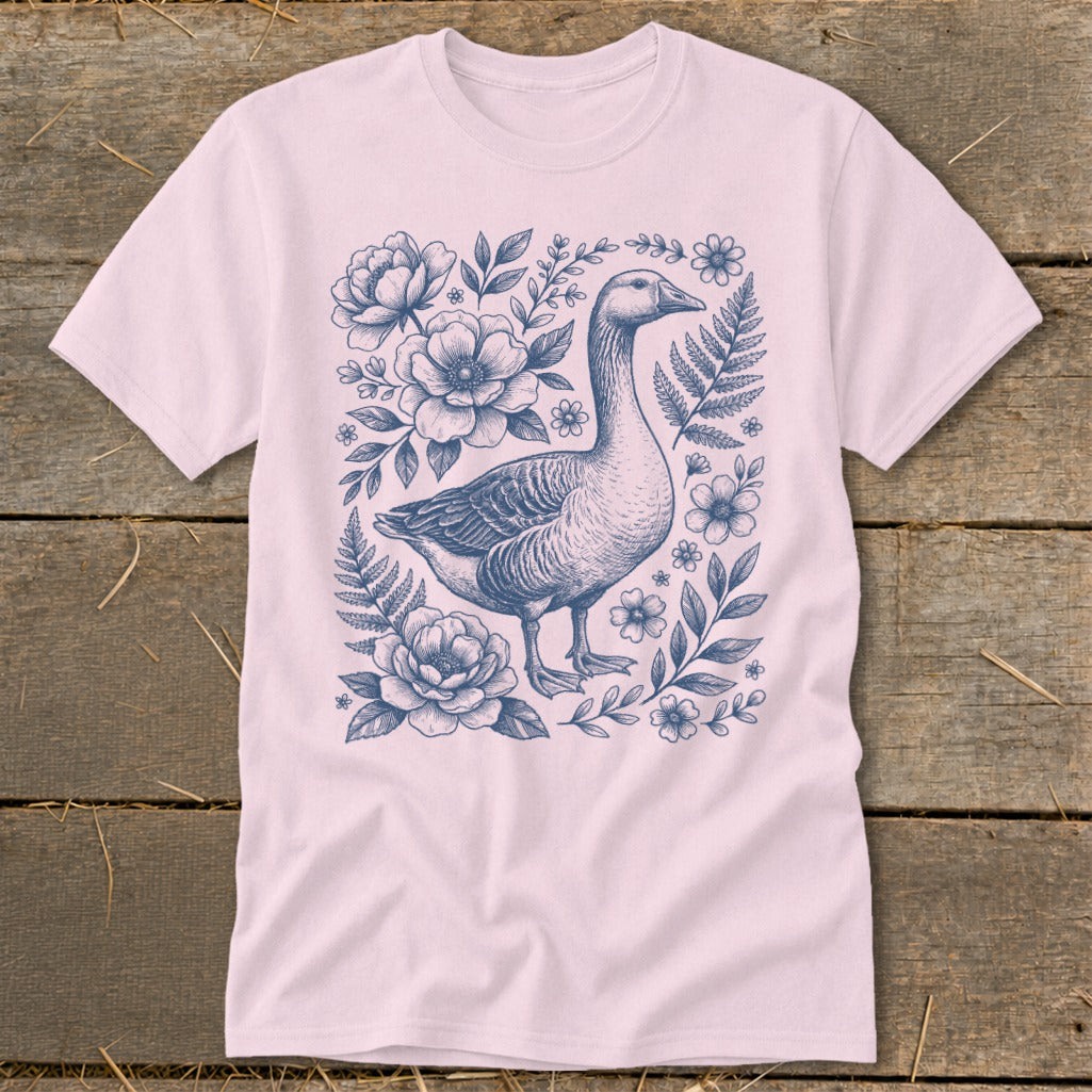 Pink t-shirt with a blue goose illustration surrounded by flowers and ferns.