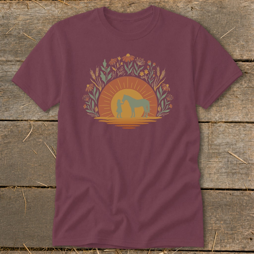 Maroon t-shirt with a sunset graphic of a girl and horse among flowers.