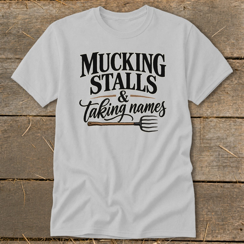 White t-shirt with "Mucking Stalls & Taking Names" text and pitchfork graphic.