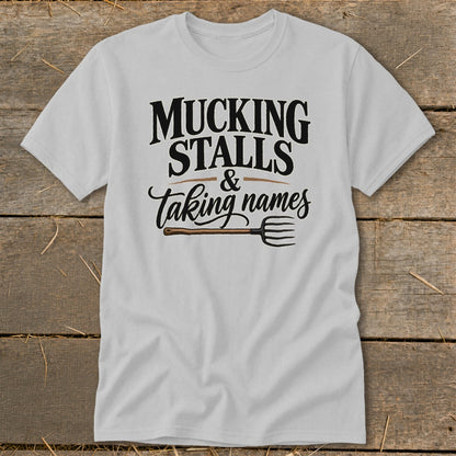 White t-shirt with "Mucking Stalls & Taking Names" text and pitchfork graphic.