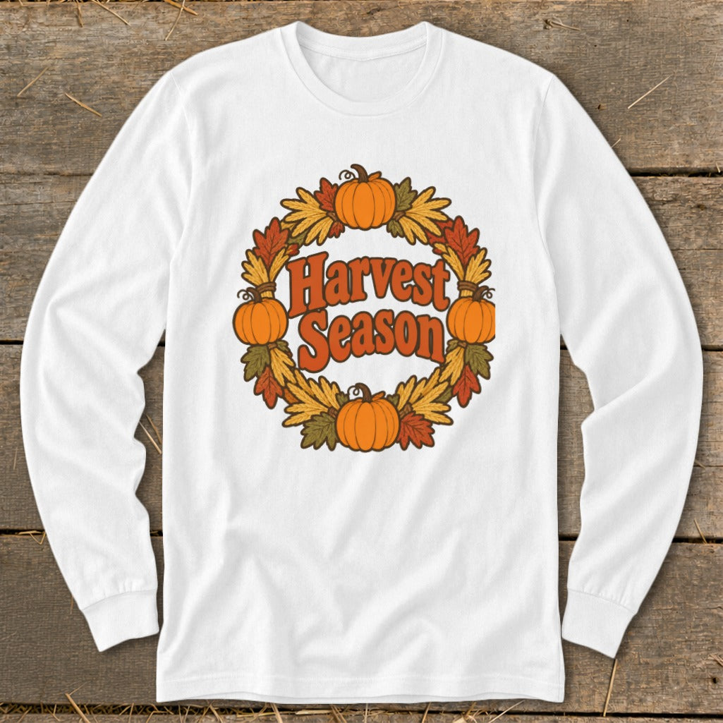 White long-sleeve shirt with "Harvest Season" text surrounded by a pumpkin and leaf wreath.