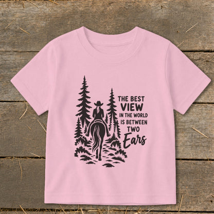 A pink t-shirt featuring a black graphic of a horseback rider among trees and text.