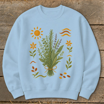 Light blue sweatshirt with botanical illustration of herbs and flowers with sun and waves.