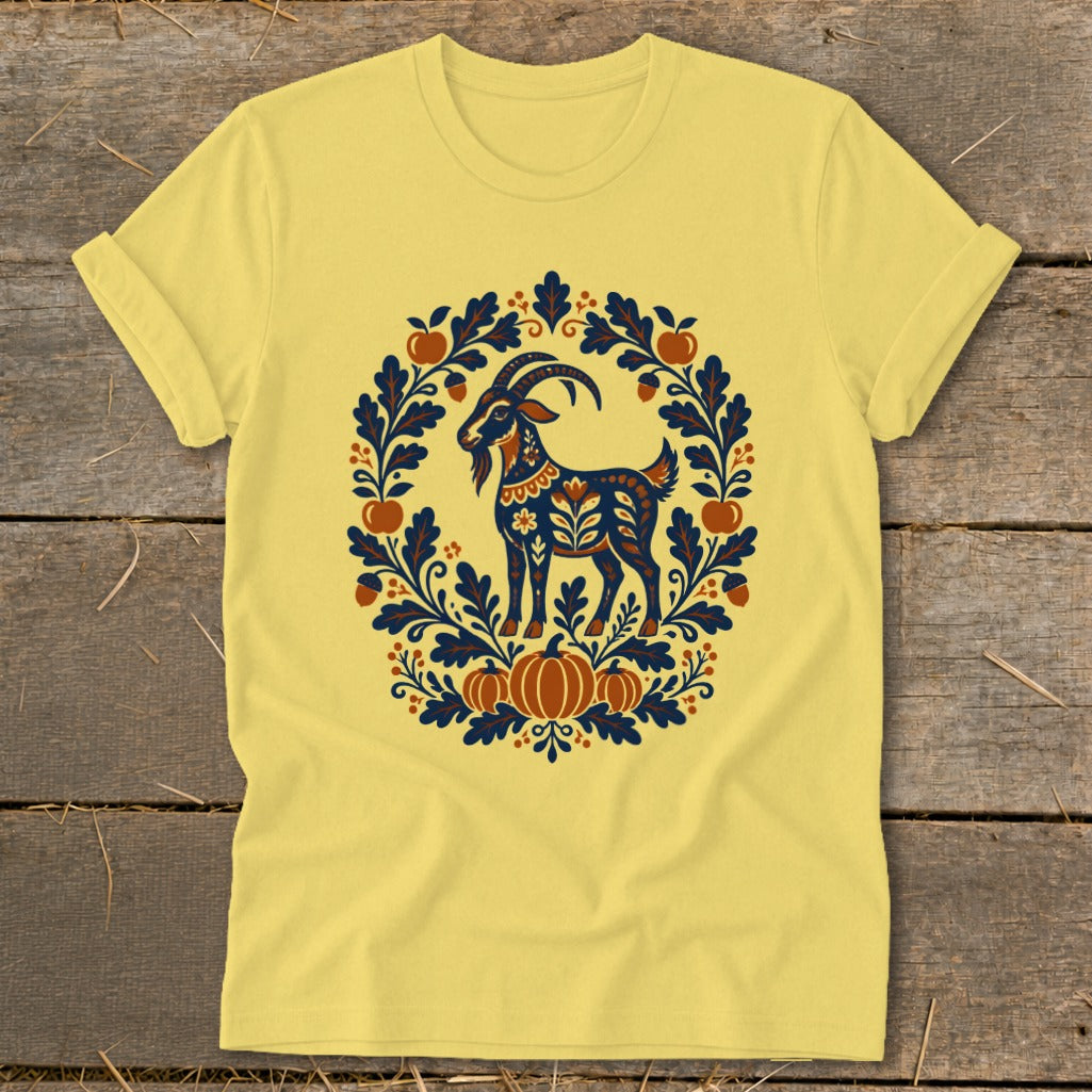 Yellow crewneck t-shirt featuring a folk art illustration of a goat surrounded by autumn leaves and pumpkins.