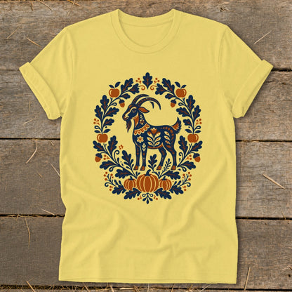 Yellow crewneck t-shirt featuring a folk art illustration of a goat surrounded by autumn leaves and pumpkins.