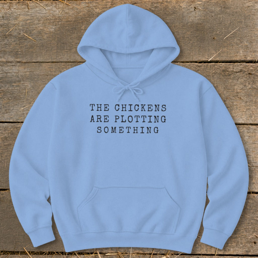 Light blue hoodie with black text that reads "THE CHICKENS ARE PLOTTING SOMETHING".