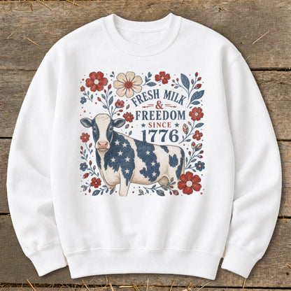 White sweatshirt with a cow wearing a starry pattern and patriotic floral art.