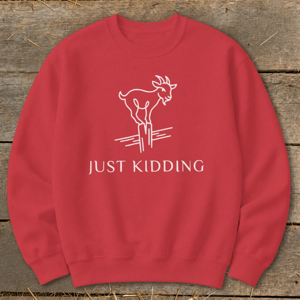 Red crewneck sweatshirt with white goat graphic and "JUST KIDDING" text.