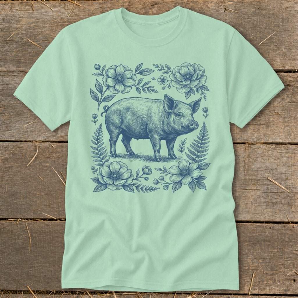 T-shirt with a blue line drawing of a pig surrounded by flowers and ferns.