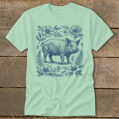 T-shirt with a blue line drawing of a pig surrounded by flowers and ferns.