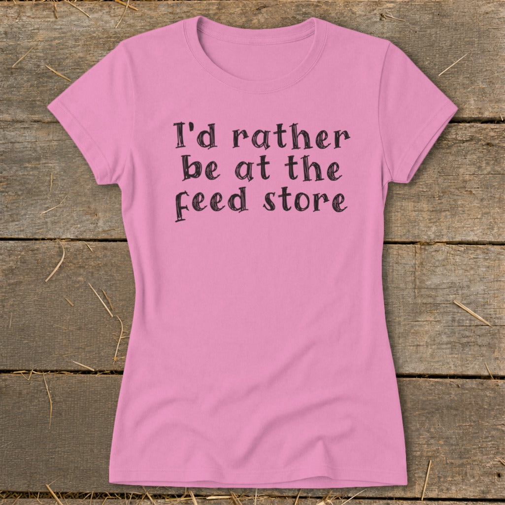 Pink t-shirt with black text reading "I'd rather be at the feed store."