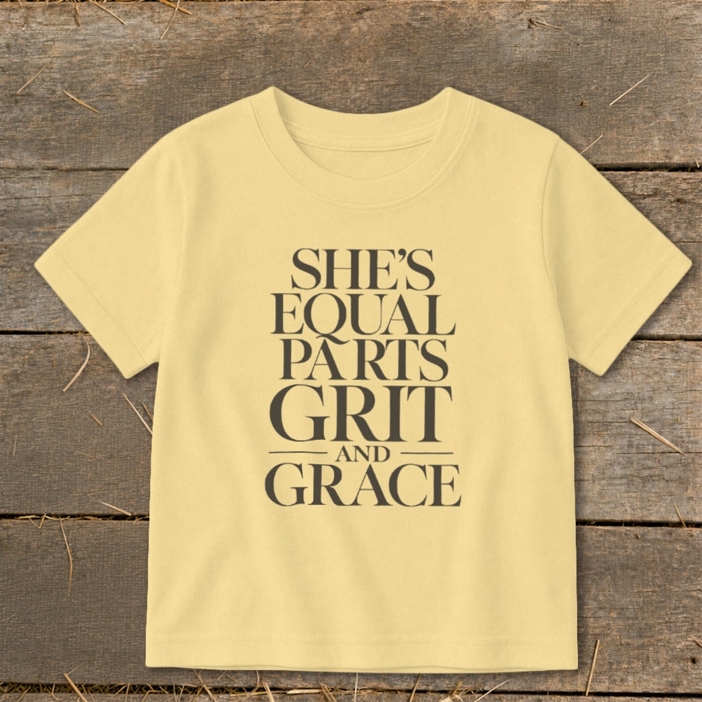Light yellow t-shirt with "She's Equal Parts Grit and Grace" text in dark gray.