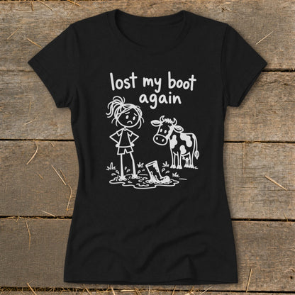 Black t-shirt featuring a white graphic of a sad girl standing next to a cow near a muddy boot, with text reading lost my boot again.