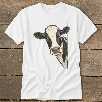 Black and white cow peeking from behind a white t-shirt on a wooden background.