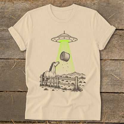 UFO beaming a hay bale onto a curious horse in a fenced pasture.