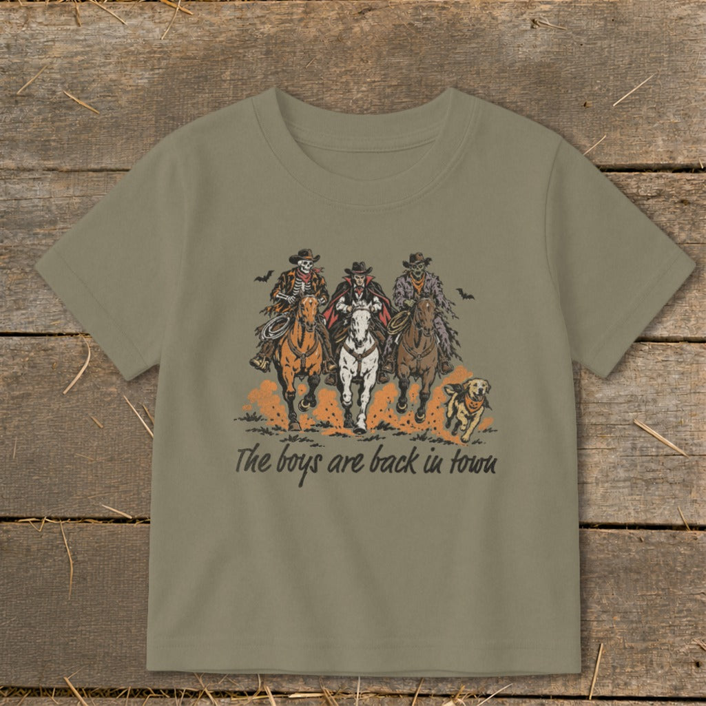 Skeleton, vampire, and zombie cowboys ride horses with a dog, text reads "The boys are back in town".