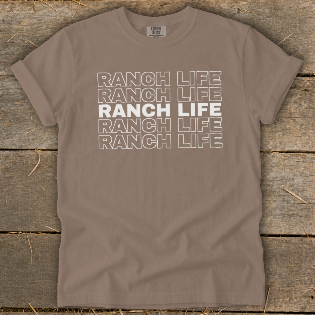 A brown crewneck t-shirt with rolled sleeves features white stacked text that reads RANCH LIFE.