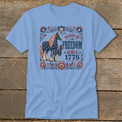Light blue t-shirt with American flag horses and "Raised on Freedom Since 1776" text.