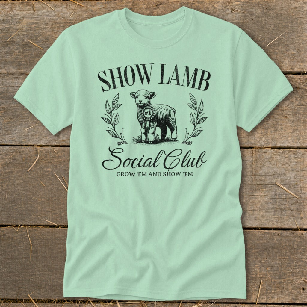 Light green t-shirt with a graphic of a lamb, ribbons, and text: SHOW LAMB SOCIAL CLUB.
