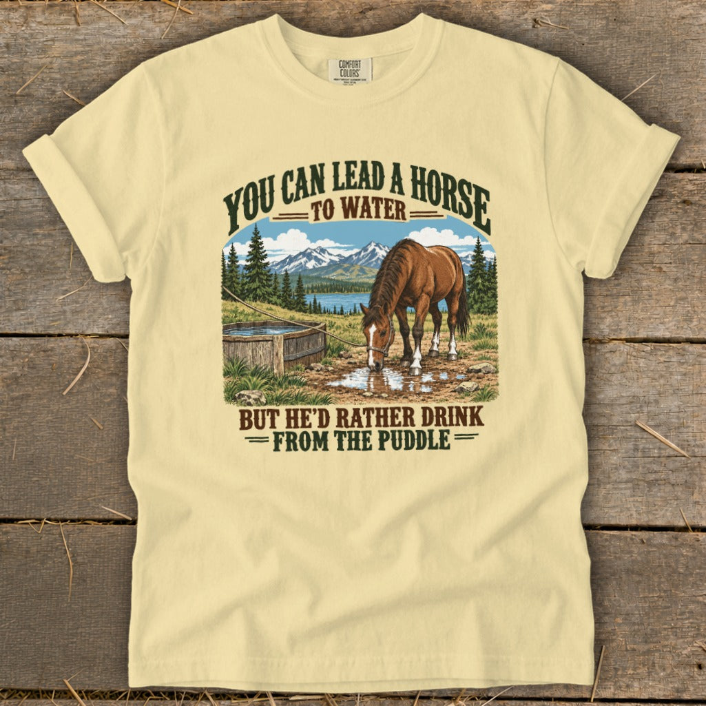 A light yellow t-shirt with a vintage graphic of a horse drinking from a puddle.